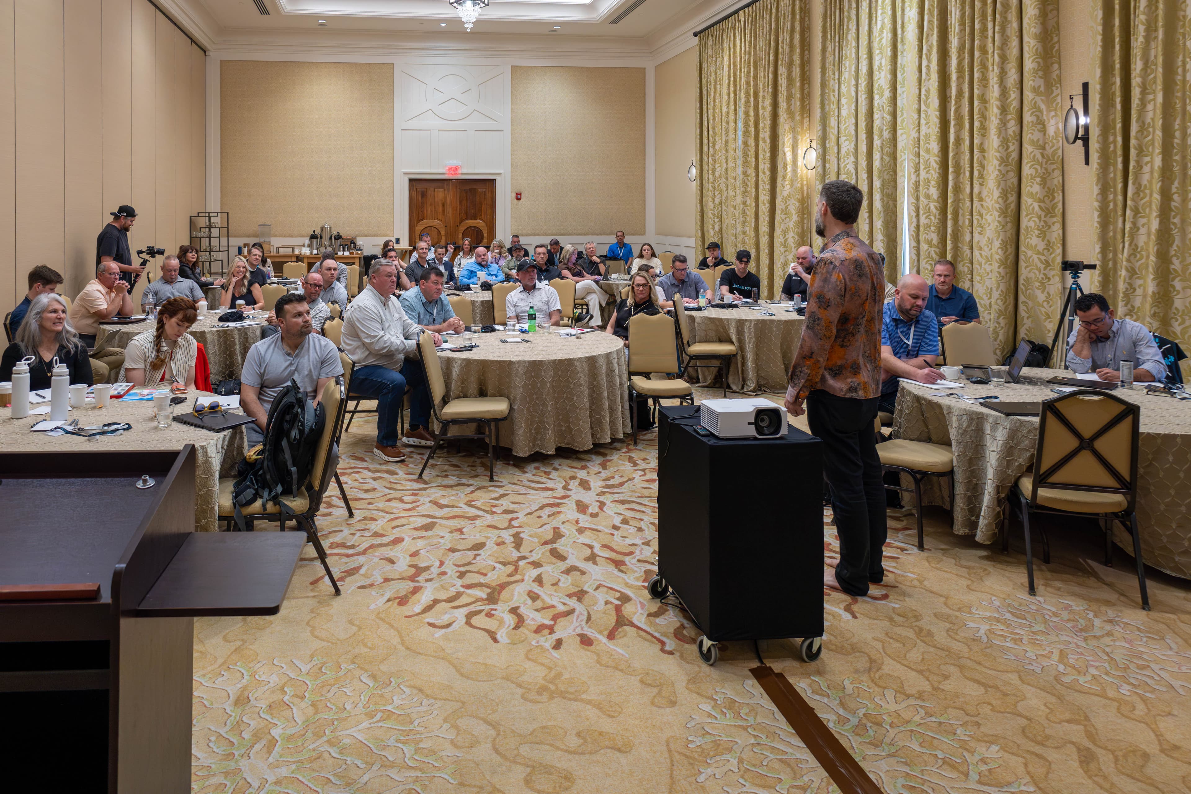 Full room of engaged attendees at round tables